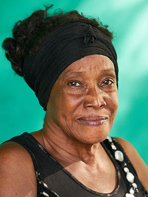 Old Cuban people and emotions, portrait of happy senior african american lady looking at camera. Copy space on green wall in background.