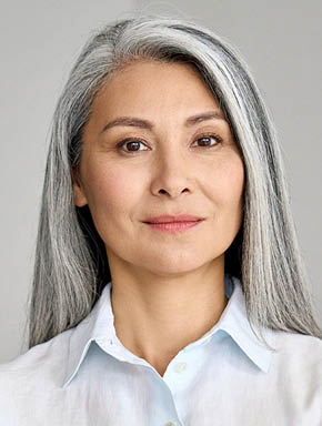 Stylish confident adult 50 years old Asian female psychologist standing arms crossed looking at camera at gray background. Portrait of sophisticated grey hair woman advertising products and services.
