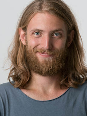 Closeup photo of young guy with a beard, blond hair to the shoulders and blue eyes looking happy one corner of the lips is raised in a smile, isolated over white background.