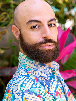 A portrait of a man with a beard in a blue shirt with prints 
